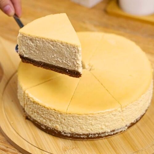 Yogurt cheesecake slice with graham base on wooden chopping board