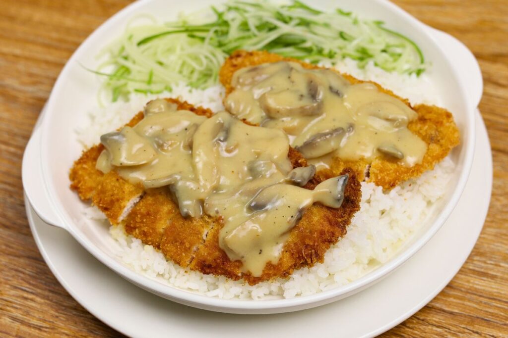 Crispy golden chicken cutlet topped with creamy mushroom sauce and served on a plate