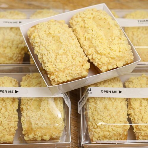 Lemon Crumb Loaf packaged in a 4×4-inch pastry box with a clear cover, showing one freshly baked mini lemon loaf with buttery crumb topping.