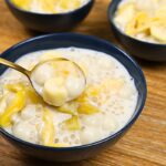 A serving bowl of creamy Ginataang Bilo-Bilo with glutinous rice balls, sweet potatoes, saba bananas, tapioca pearls, and jackfruit scooped with a spoon.